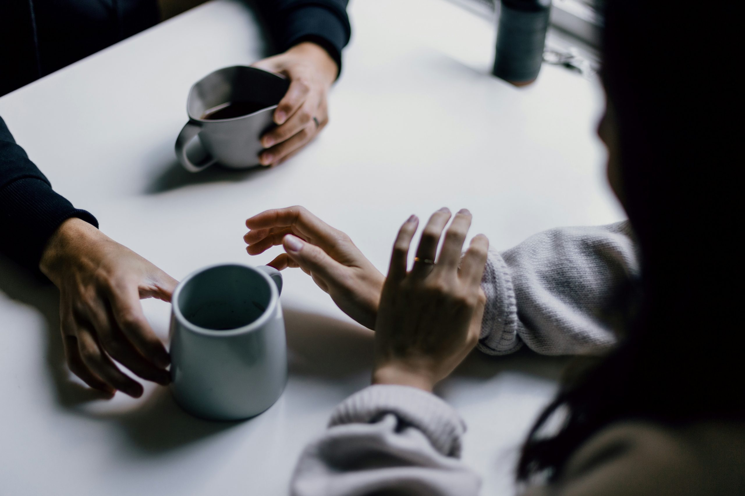 Image of two people talking across a table drinking coffee
